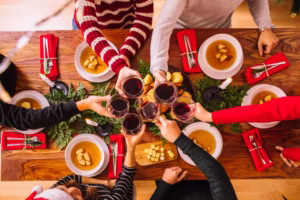 Bariatric Holiday Recipes: hands clink glasses of red wine over a festive table with soup bowls and red napkins