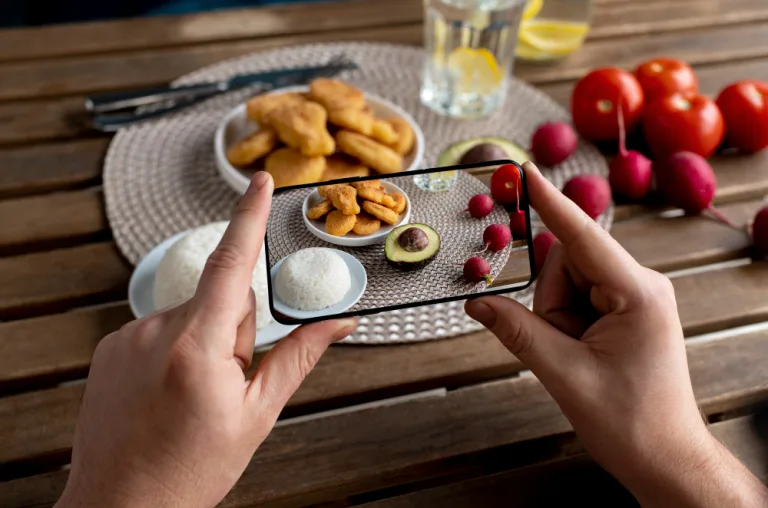 Diabetic Holiday Meals: a hand photographs a plate of roast potatoes, radishes and tomatoes with a smartphone