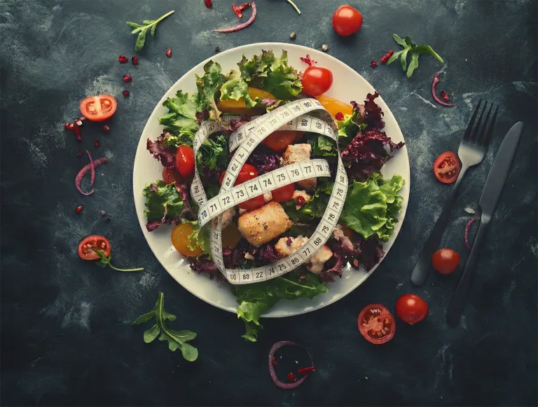Plate of mixed salad with tomatoes and croutons topped with a measuring tape.